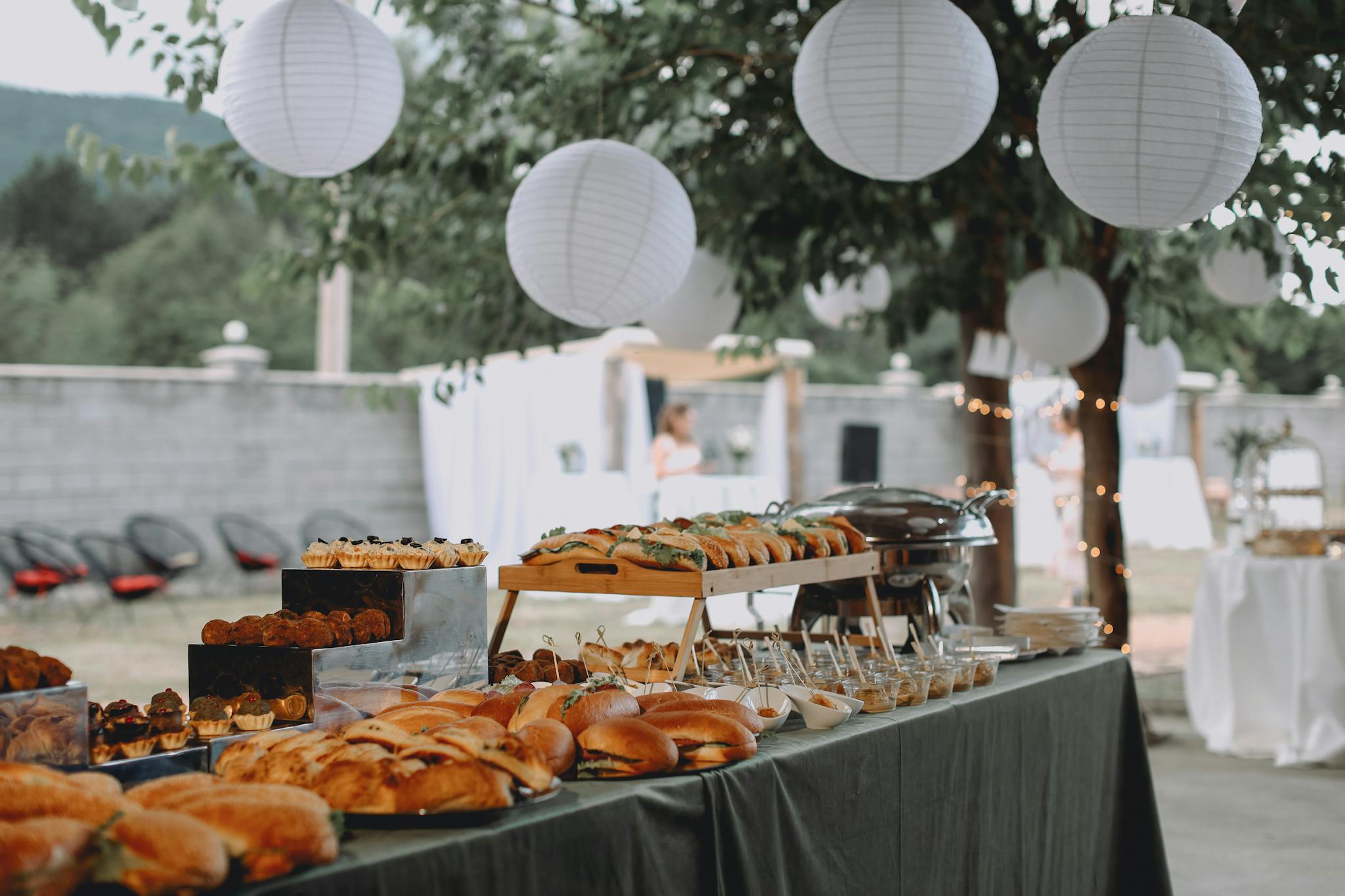 an elegant outdoor buffet featuring sandwiches and pastries under decorative lanterns. 27025523 2048x1365 1 3minutesfood Catering จากเกษตรอินทรีย์ ร่วมส่งต่อความยั่งยืน
